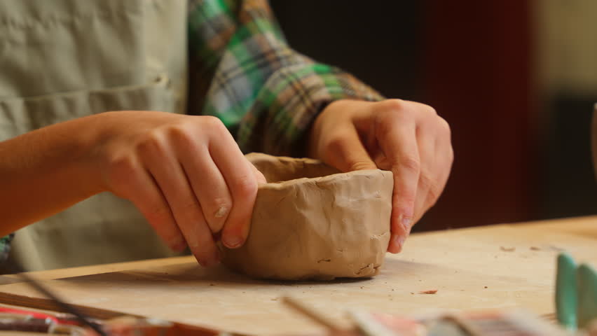 Close up focused creative talented Caucasian little girl school child kid student hands shape modeling clay dirt shaping bowl plate crafts ceramic pottery art handmade artwork indoors workshop studio