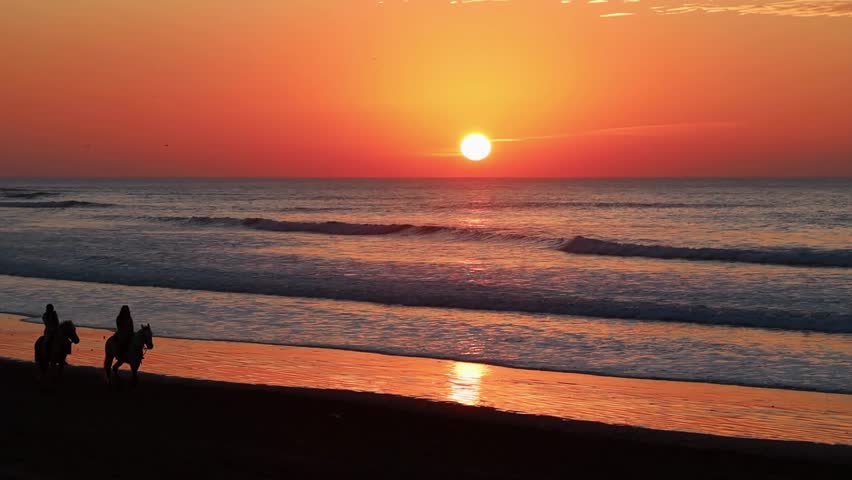 People riding horses along the beach at sunset Atlantic coast Essaouira Morocco