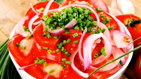 healthy food : fresh tomato salad in white bowl with bunch of chives and raw tomatoes on twig onion and garlic over wooden table