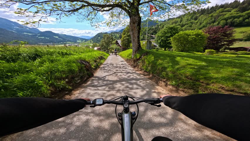 POV man riding mountain e-bike with scenic mountain view. Freedom concept of a tourist man riding a bicycle on mountain trail. Travel summer activities in Swiss Alps