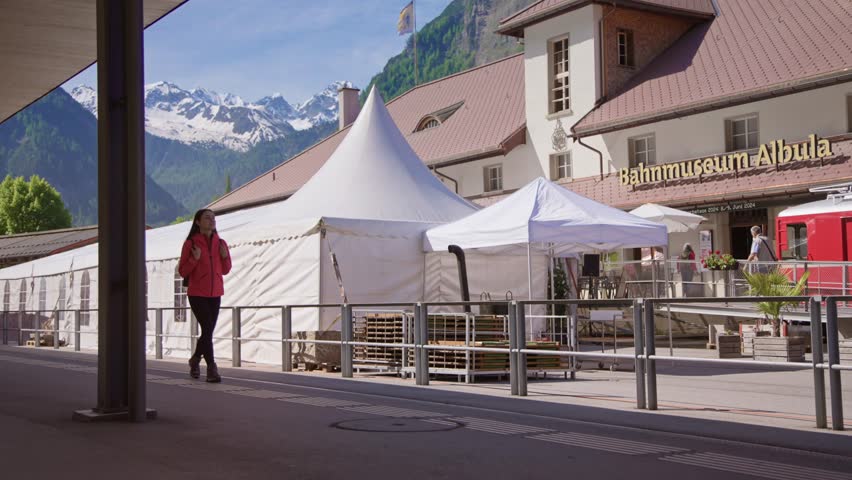 Travel video of a tourist woman walking in the train station with a stunning view of the Alps. Perfect for lifestyle, travel, vacation, and adventure in the Swiss Alps