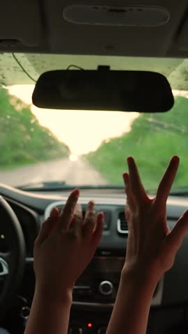 Happy travels of young women by car. Driver, cheerful girlfriends dancing in car enjoying trip on road. Adventures and travels in car. Happy friends cheerfully dancing listening to music. Slow Motion