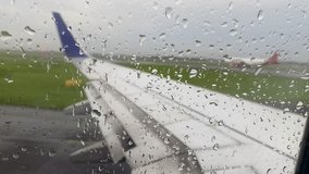 view of airplane wing from airplane window while drizzle and raindrops on the window glass and the airplane is about to take off on runway - Powered by Shutterstock - Get 15% off with code: PIKWIZARD15