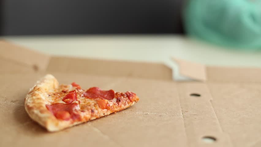 A child takes the last slice of pizza from a box in close-up