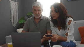 Middle-aged couple sitting together using laptop happily at home interior for online shopping with credit card in living room. - Powered by Shutterstock - Get 15% off with code: PIKWIZARD15