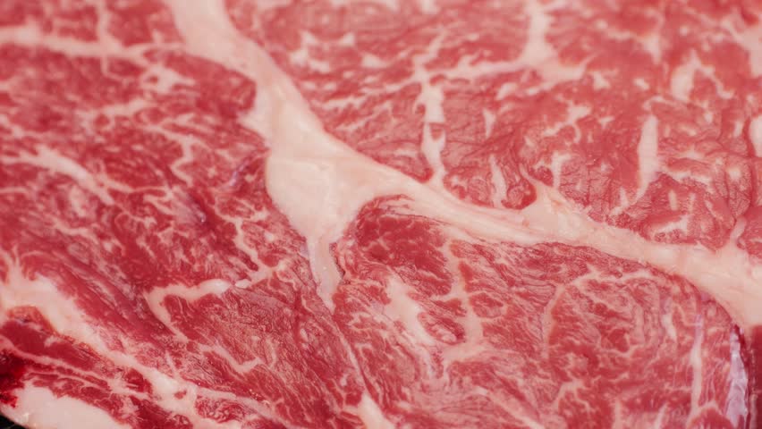 Fresh marbled beef with pepper, salt and rosemary close-up macro. Preparation to cook juicy steak on grill. Premium organic raw wagyu meat