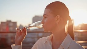 Elegant girl drinking champagne at sunset rooftop closeup. Beautiful woman sipping sparkling wine from glass goblet at evening outdoor party. Smiling lady enjoying weekend celebration on terrace. - Powered by Shutterstock - Get 15% off with code: PIKWIZARD15