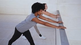 Two young women doing calf stretching exercises outdoors - Powered by Shutterstock - Get 15% off with code: PIKWIZARD15