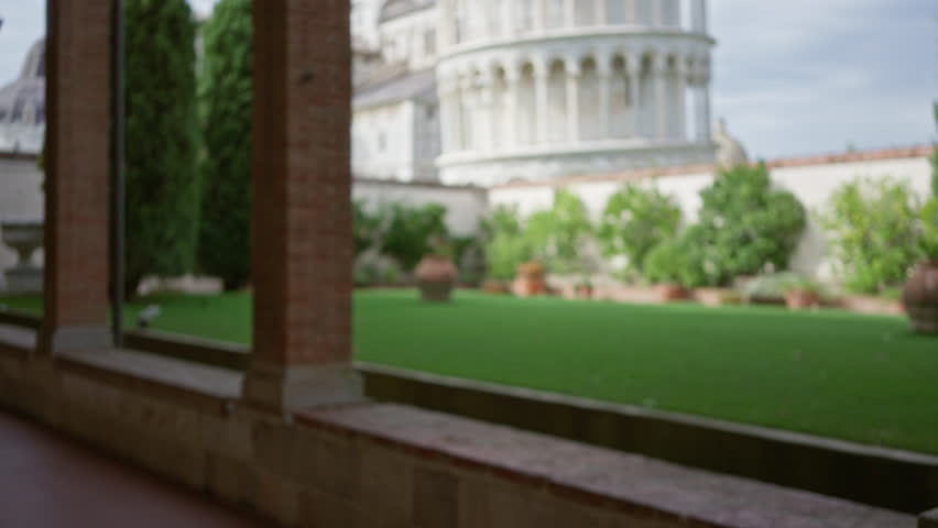 Defocused view of pisa monument with blurred garden and trees in italy showcasing iconic architecture and serene greenery under a soft bokeh effect captured in daylight.