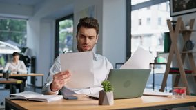 Business manager reading report at modern workspace closeup. Focused businessman dissatisfied documents sitting workplace with laptop. Sad executive reviewing financial data on papers feeling stress. - Powered by Shutterstock - Get 15% off with code: PIKWIZARD15