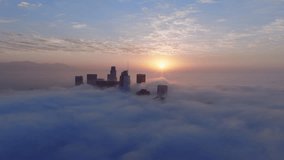 Breathtaking Aerial drone view of Downtown Los Angeles skyline is bathed in morning light, rising above a thick blanket of fog and swirling clouds, creating an enchanting atmosphere at sunrise - Powered by Shutterstock - Get 15% off with code: PIKWIZARD15