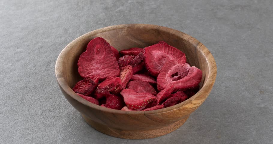 Freeze-dried strawberries in a wooden bowl. Close-up footage on the rotating table.