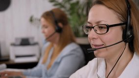 A smiling, friendly female call center agent with glasses and a headset works on the office support hotline. - Powered by Shutterstock - Get 15% off with code: PIKWIZARD15