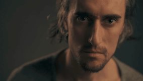Intense Gaze Young European man with striking big eyes and long hair stares seriously into the lens then menacingly narrows his eyes - Powered by Shutterstock - Get 15% off with code: PIKWIZARD15