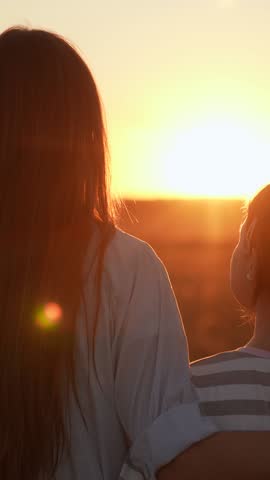 Mom child hugs together on sunny day. Happy daughter hugs mother in nature. Child girl hugging her mother in summer park. Happy family on walk in field looking to future. Carefree childhood mom kid