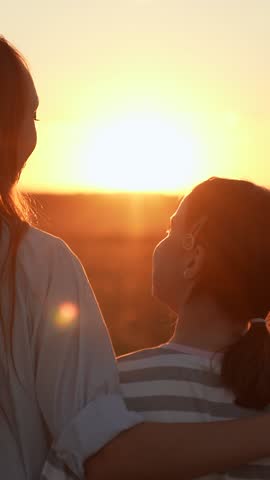 Mom child hugs together on sunny day. Happy daughter hugs mother in nature. Child girl hugging her mother in summer park. Happy family on walk in field looking to future. Carefree childhood mom kid