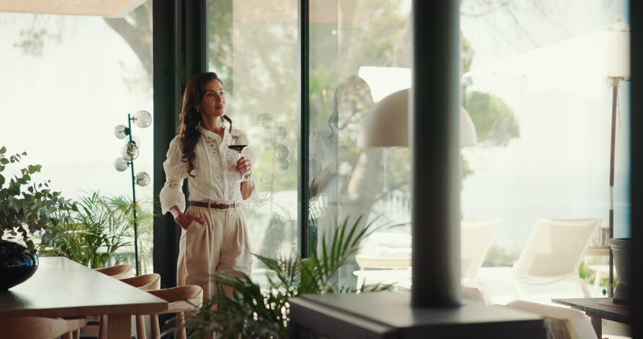 Thinking, woman and wine in home for relax, peace or calm by window view for reflection. Alcohol glass, living room and person with beverage, dream or remember memory on weekend break in luxury house
