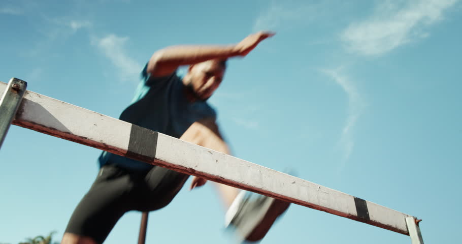 Below, man and jump for hurdle outdoor of fitness competition, run exercise and sports performance. Male athlete, running and obstacle race for cardio training, workout challenge and endurance goals