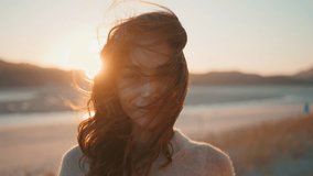 Portrait woman at windy sunset nature looking camera. Beautiful brunette posing in front golden evening horizon with windblown hair closeup. Happy woman enjoying serene summer twilight standing alone. - Powered by Shutterstock - Get 15% off with code: PIKWIZARD15