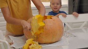 Family making Halloween pumpkin Jack-o-lantern at home. Carving large orange pumpkin for Halloween, making scary face on jack o lantern. Autumn season. Thanksgiving Day. - Powered by Shutterstock - Get 15% off with code: PIKWIZARD15