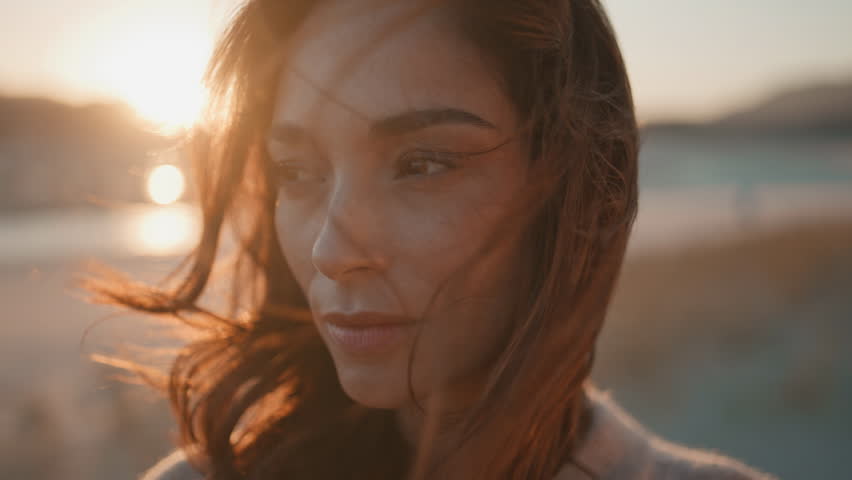 Sensual girl posing sunlight with dark hair swaying in wind closeup. Gorgeous woman closing eyes enjoy serene sunset on beautiful nature. Tranquil brunette model standing at golden evening skyline.