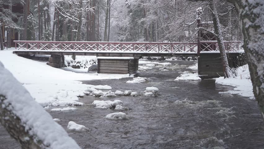 Witness a breathtaking aerial view of the Kotka river in Finland, surrounded by beautiful snowy terrain. The landscape showcases winter