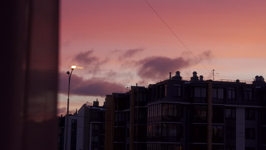 Red clouds lit by the morning sun over an apartment building, dawn in a residential area.
