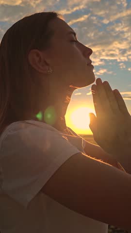 Girl relax. Young woman praying at sunset, Silhouette. Path of soul to God through prayer. Christian prayer, nature. Morning prayer of girl outdoors. Freedom of religion. Era of mercy, kindness, love.