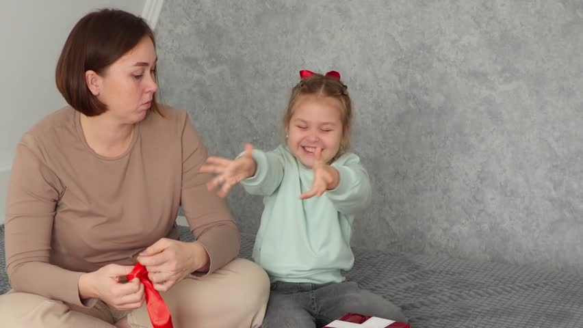 Mid shot of Caucasian mother and daughter pack a gift for the holiday together. Concept of preschool education and Valentine