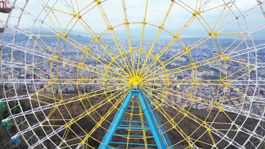 Dynamic aerial drone footage flying past the Ferris wheel on Mtatsminda Mountain, Tbilisi, Georgia. 