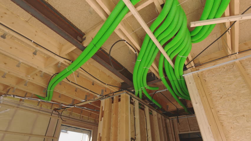 Air condition duct is being installed in a modern construction site. The project involves wooden framing and a complex arrangement of pipes overhead.