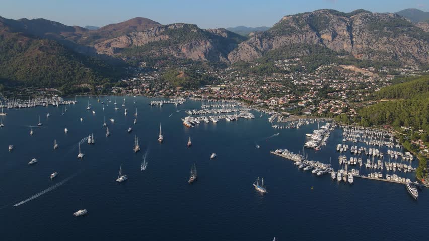 Beautiful blue ocean with many boats in it. The boats are of different sizes and are scattered throughout the water. The scene is peaceful and serene, with the boats floating on the calm water