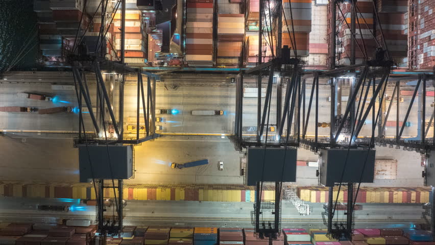 Aerial hyperlapse timelapse of cargo ship loading and unloading with crane at night. Industrial shipyard, containers, car traffic, freight transportation, International business logistics industry. 