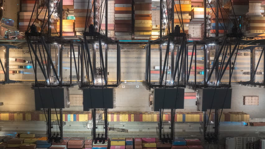 Aerial hyperlapse timelapse of cargo ship loading and unloading with crane at night. Industrial shipyard, containers, car traffic, freight transportation, International business logistics industry. 