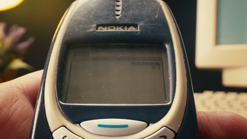 BARCELONA, SPAIN, 15 DECEMBER 2024: Man arm holding Nokia 3310 phone cellphone, vintage retro mobile phone, text message sms.