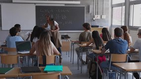 Experienced chemistry teacher handing out tests to her attentive high school students. Education lifestyle concept. - Powered by Shutterstock - Get 15% off with code: PIKWIZARD15