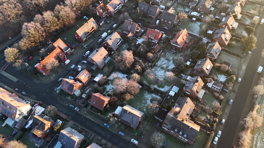 Frozen and icy neighborhood during golden sunrise. Frozen leafless trees in winter season. Aerial top down flyover. Single family houses and frosty rooftops in america. Quaint suburb district.