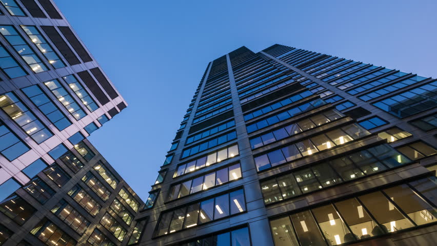 Day to night transition office windows lights time-lapse, modern high-rise skyscrapers, financial district tall glass buildings in downtown looking up wide angle shot, people working late evening - Powered by Shutterstock - Get 15% off with code: PIKWIZARD15