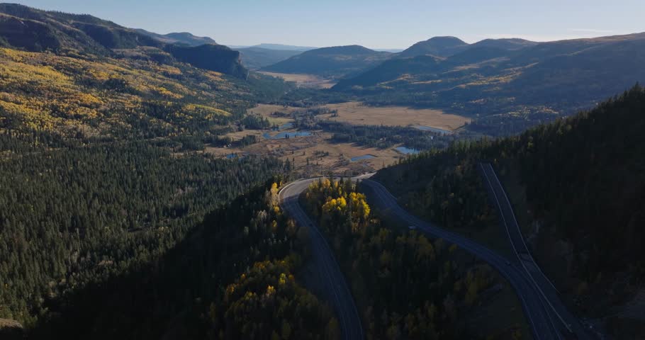 Wolf creek valley with winding road and autumn-colored trees near pagosa springs, colorado, aerial view