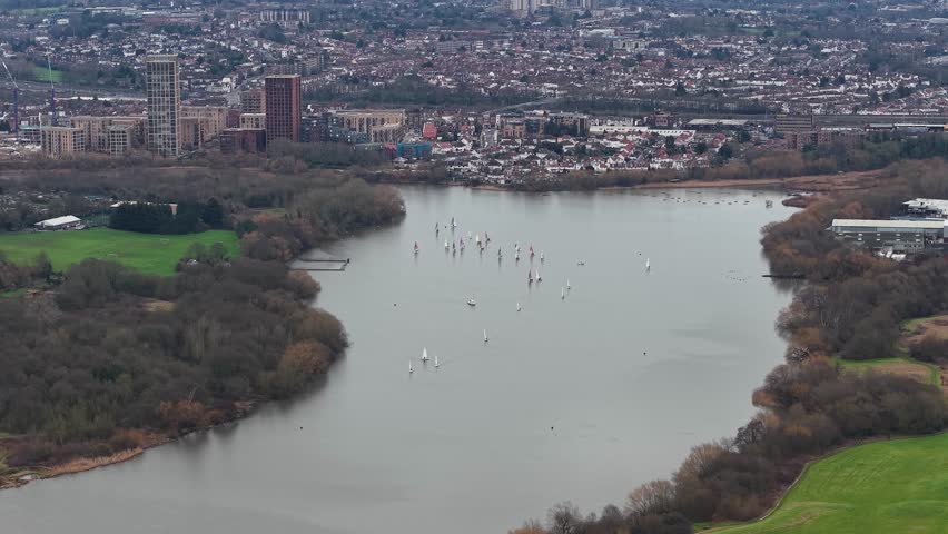 Aerial view descending over Brent reservoir lake overlooking Wembley to London city skyline