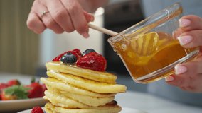 Woman pouring honey on delicious pancakes with fruit in slow motion - Powered by Shutterstock - Get 15% off with code: PIKWIZARD15