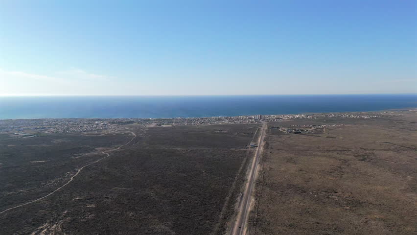 Experience a high aerial view of Las Grutas, an Argentinean resort town on the Gulf of San Matias in northern Patagonia, featuring long beaches and cliff-backed caves.