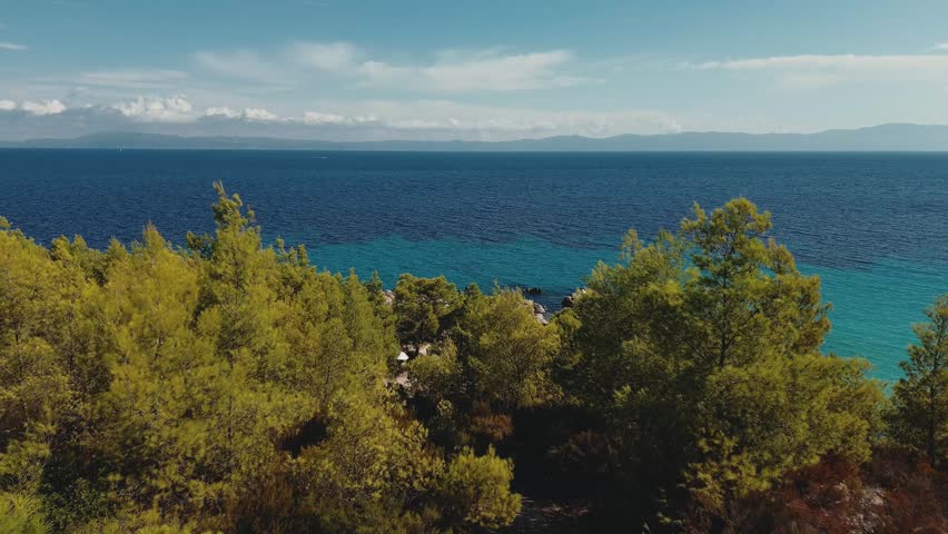 Aerial video of a beach in Greece with stunning turquoise waters during the summer. Drone photo of the picturesque beach.