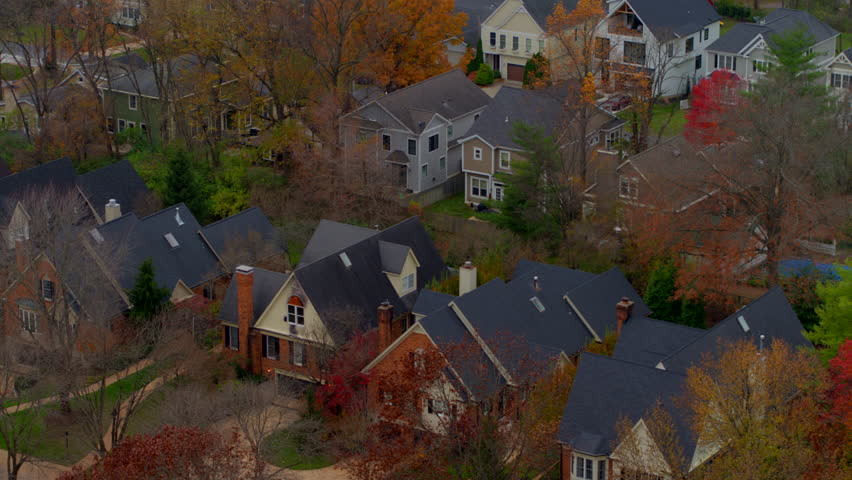 Beautiful aerial push over nice homes and vibrant trees at peak color in a St. Louis neighborhood during autumn. Captures the charm of fall foliage and suburban serenity on a clear day.