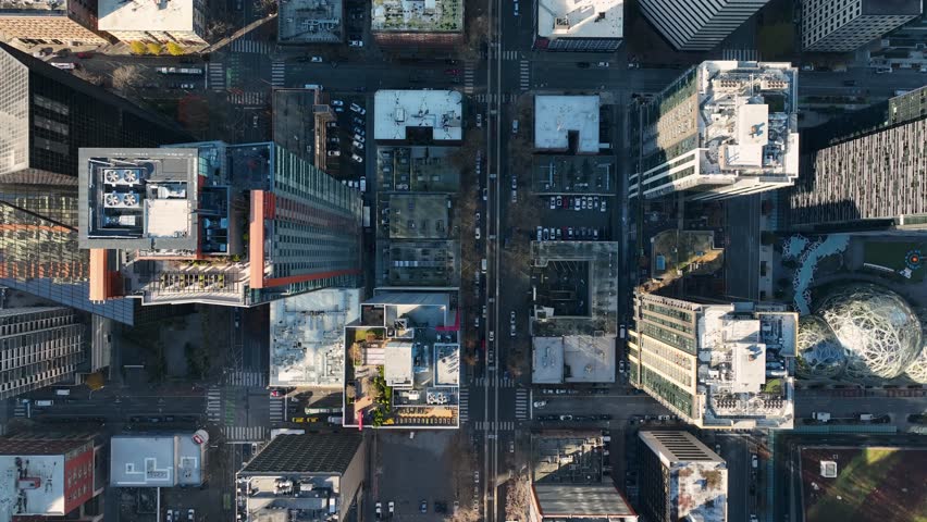 Directly above downtown Seattle street with high-rise towers, lowering aerial
