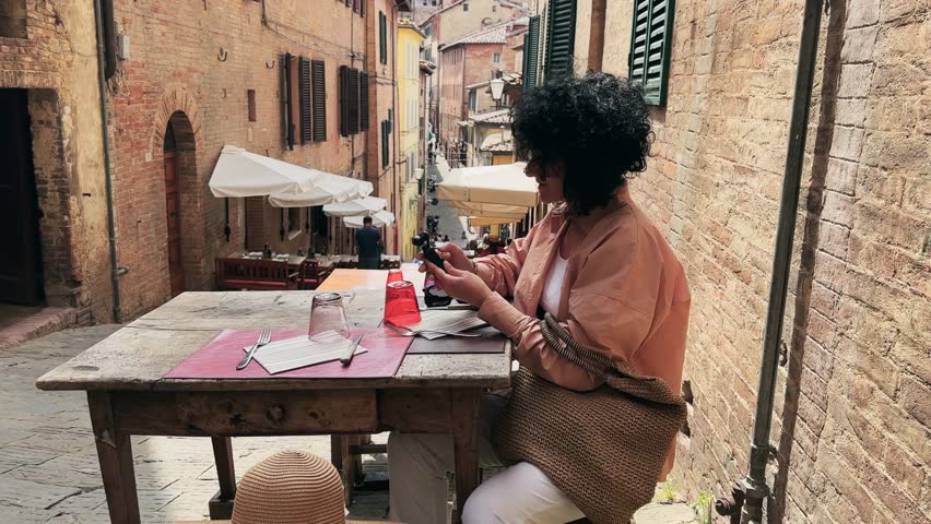 Woman sitting on restaurant dining table checking camera settings in Siena Street Setting