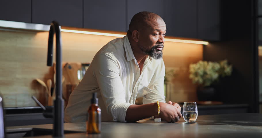 Black man, tablets and drinking water in home, health and vitamin b pills for wellness. Kitchen, container and drugs storage for chronic treatment, medication and omega 3 to remedy flu condition