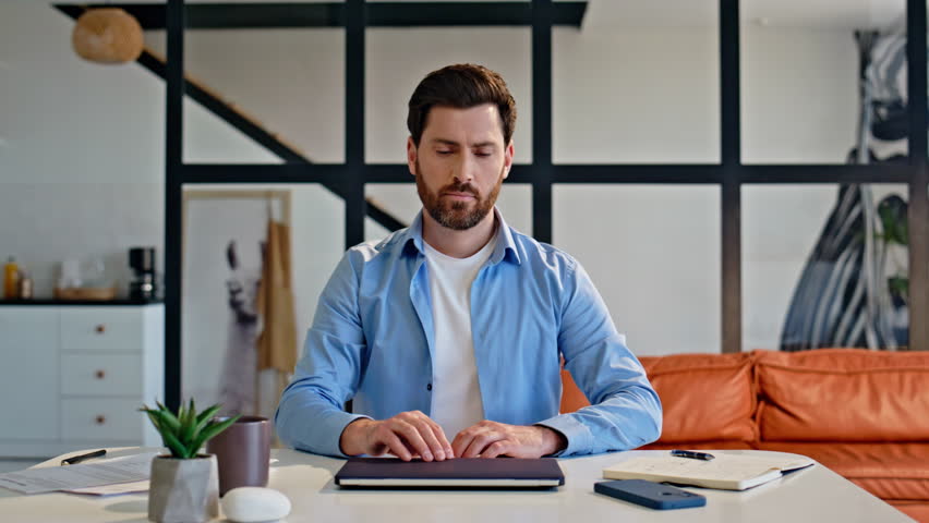 Home worker opening laptop lid sitting at cozy apartment workplace closeup. Relaxed bearded freelancer man starting remote work answering email at stylish interior. Online student watching webinar