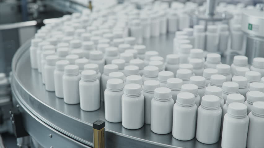 Rotary Conveyor at Pharmaceutical Production Plant with White Plastic Bottles Filled with Pills. Medication Manufacturing Process at Pharmaceutical Drug Factory