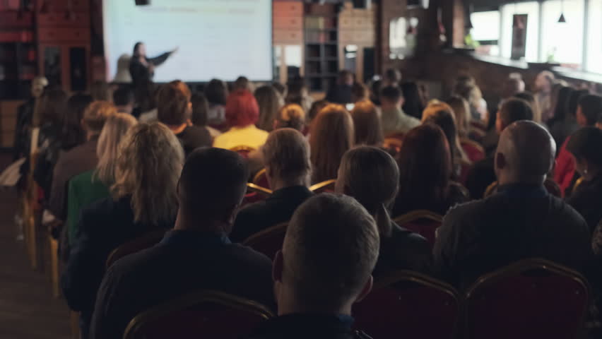 Large group of people attending educational event in comfortable indoor venue with speaker.